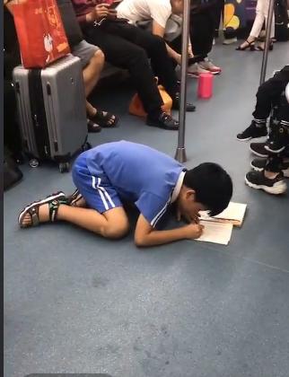地铁上小学生趴在地上写作业孩子努力的模样让人有点心疼