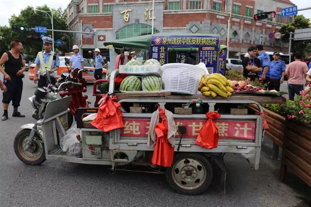 "在侨乡商品街中段,一辆电动三轮车停靠在路边贩卖水果,被区城管局
