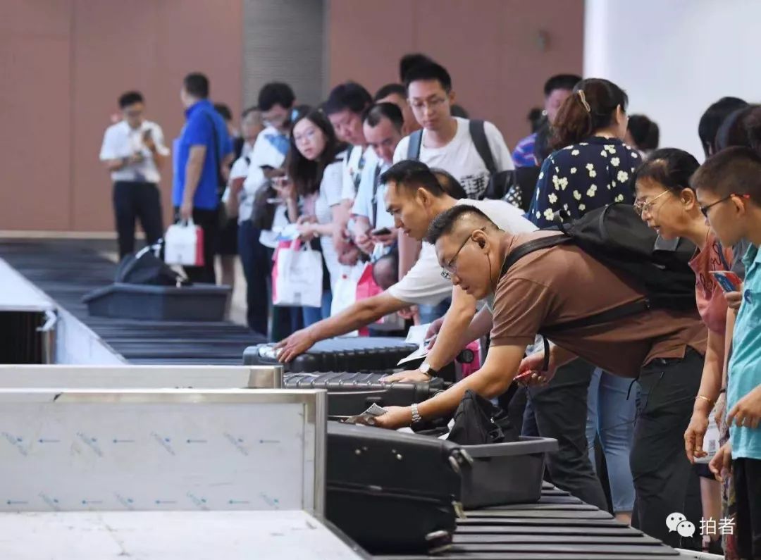 大兴机场航站楼二层的到达层内,旅客在传送带旁等待提取自己的行李