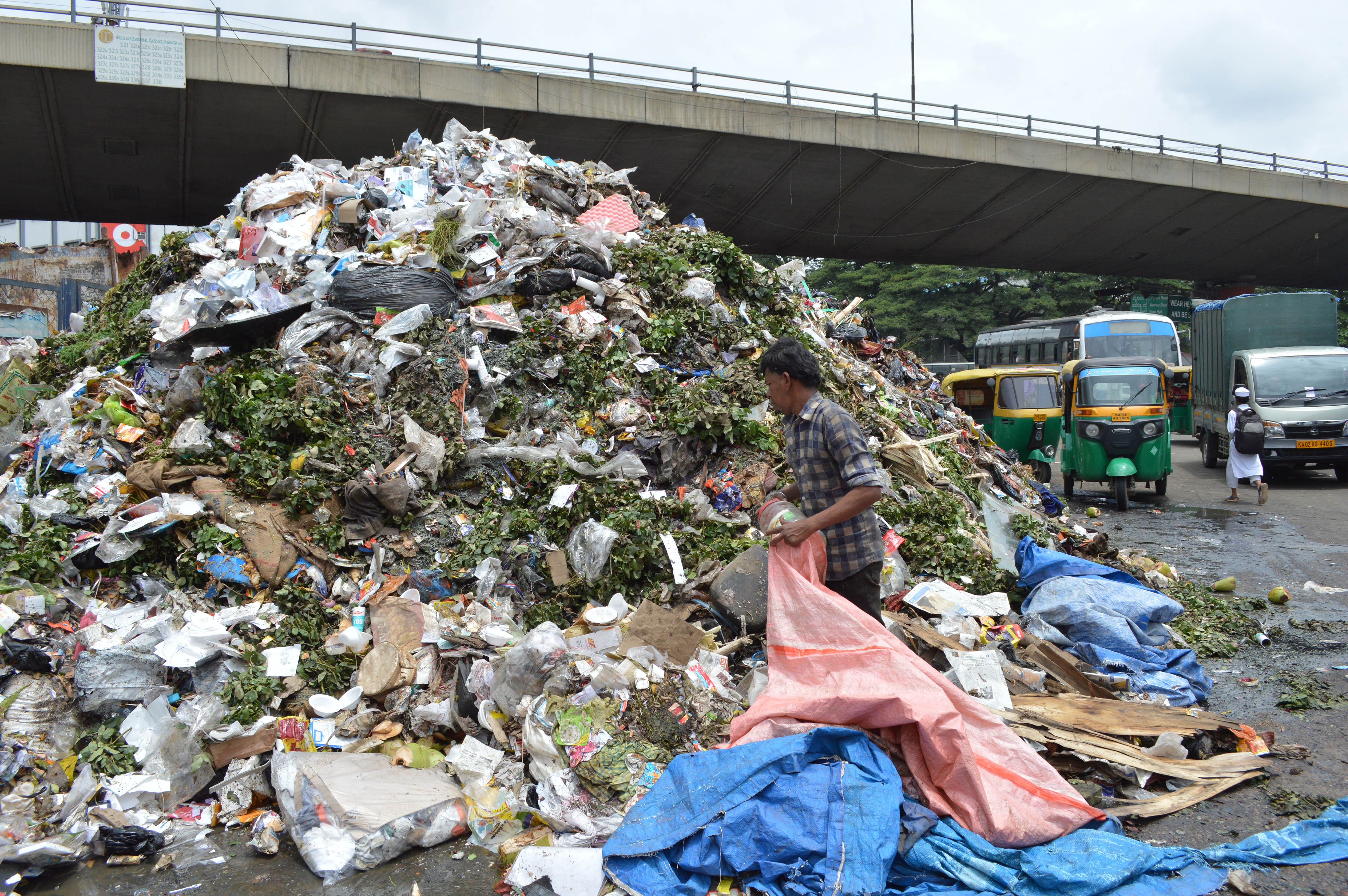 7月25日,在印度班加罗尔,人们从堆积成山的垃圾旁走过