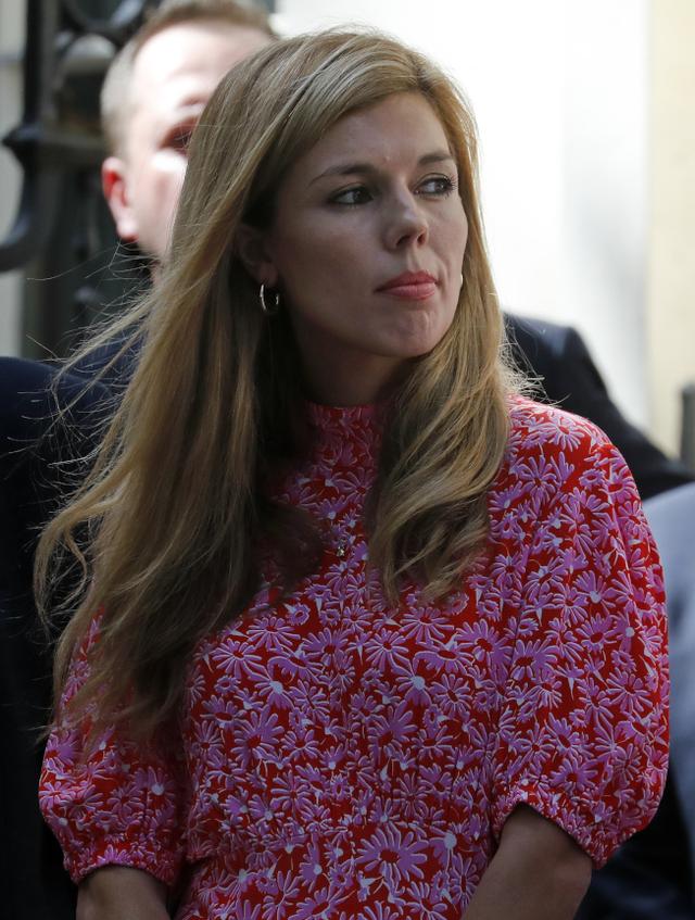 31岁的红粉知己凯莉64辛蒙兹(carrie symonds)与他的幕僚站在一旁看