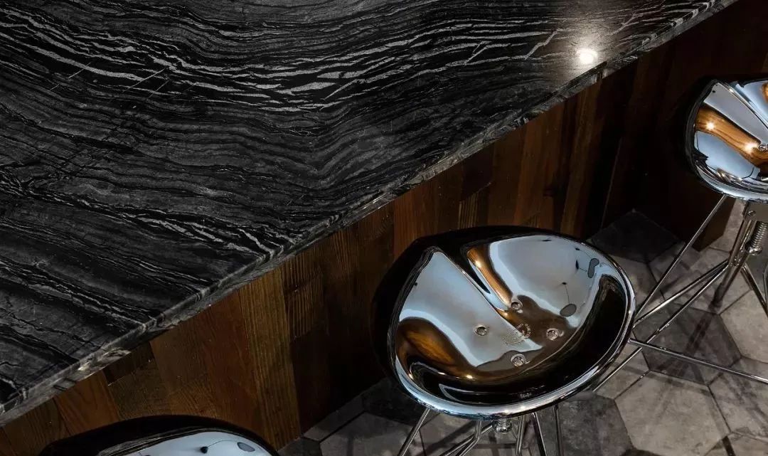旧木板制作的岛台与相同材质的吊顶相互呼应,配上黑色大理石台面有