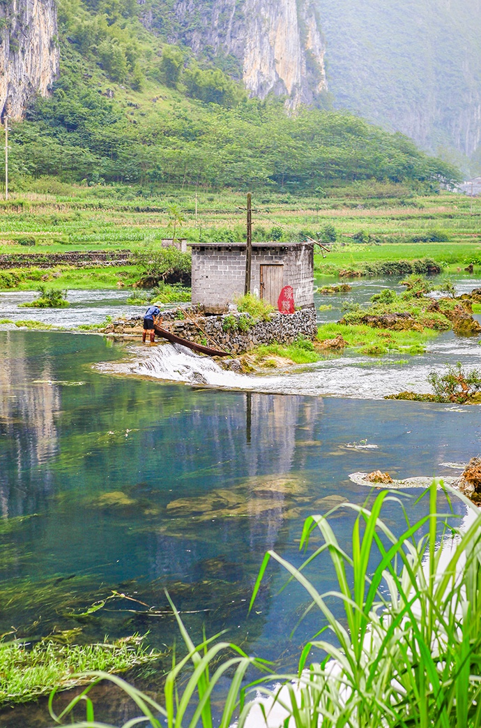 阳光照耀下,水面波光粼粼,溪边三三两两的古朴民居聚在一起,却一点不