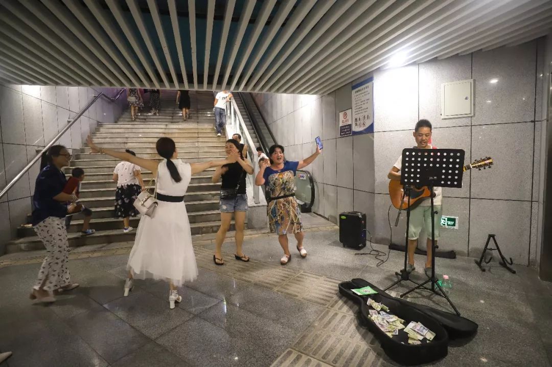 "……这样的"点歌声音"持续不断,一群人围着两个正在表演的街头艺人