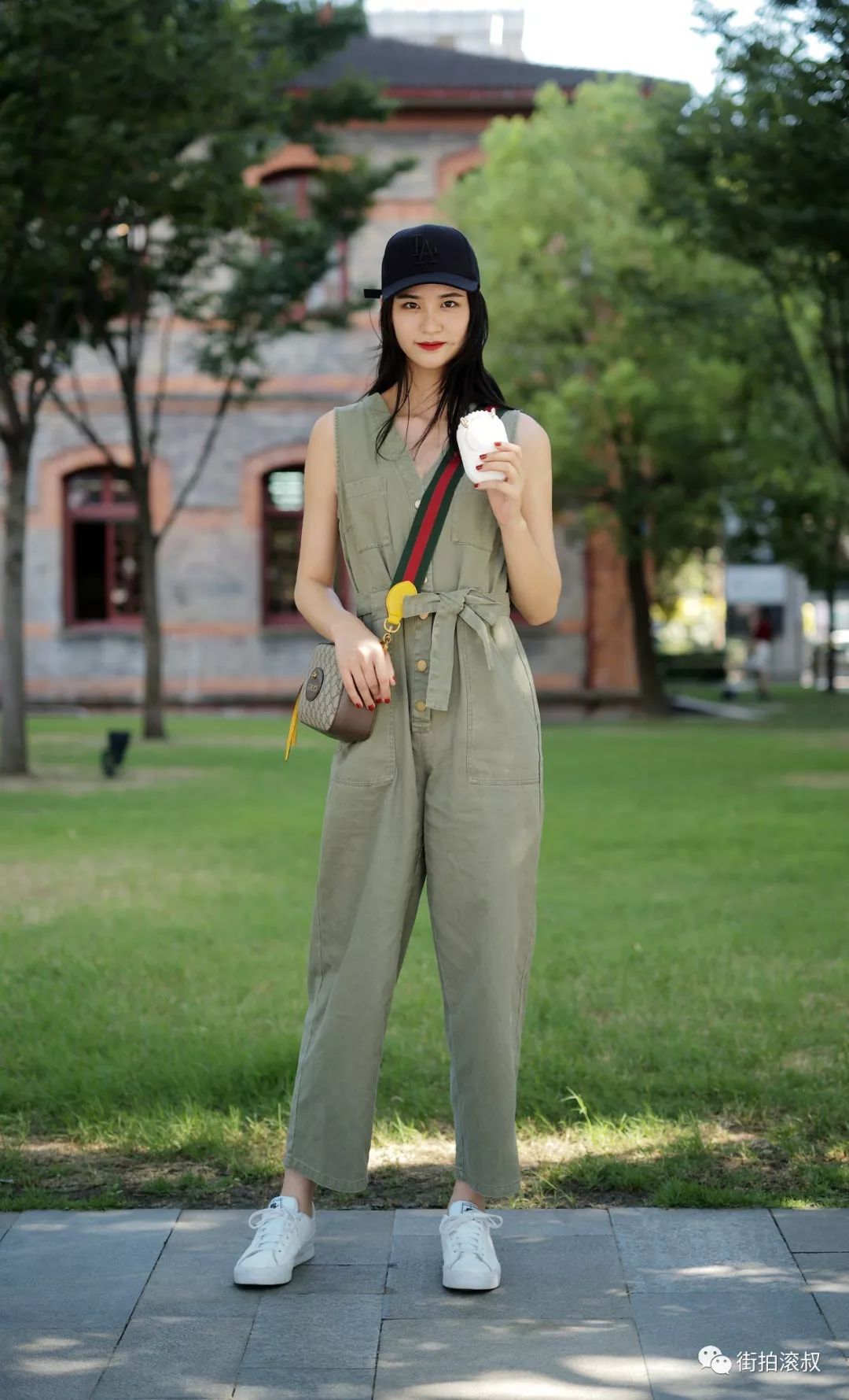 卡其绿色无袖连身裤搭配小白鞋,棒球帽是用来遮阳的这很明显,妹纸手里