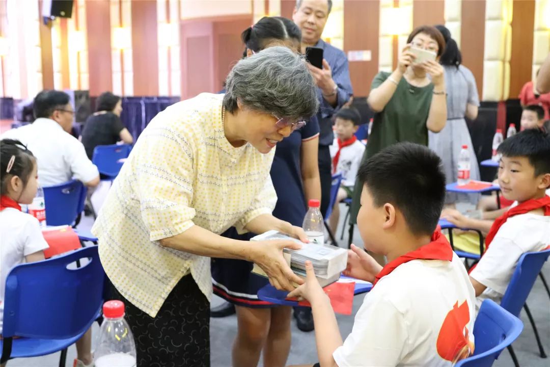 新湖集团党委书记邹丽华带着孙女向学生赠送学习用品,并对小候鸟们