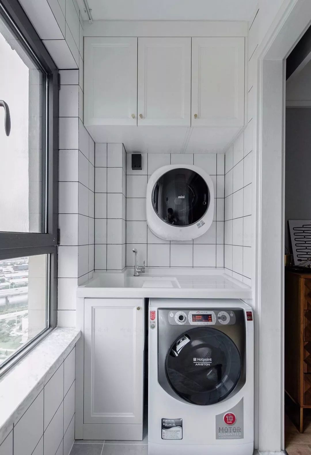 采用灰色地砖结合小白砖铺贴出清爽的洗衣阳台,配备大小洗衣机,用