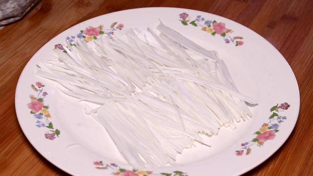 切开,把里面的芯给它取出来,切成葱丝,将葱丝摆入盘中,把葱芯切一下