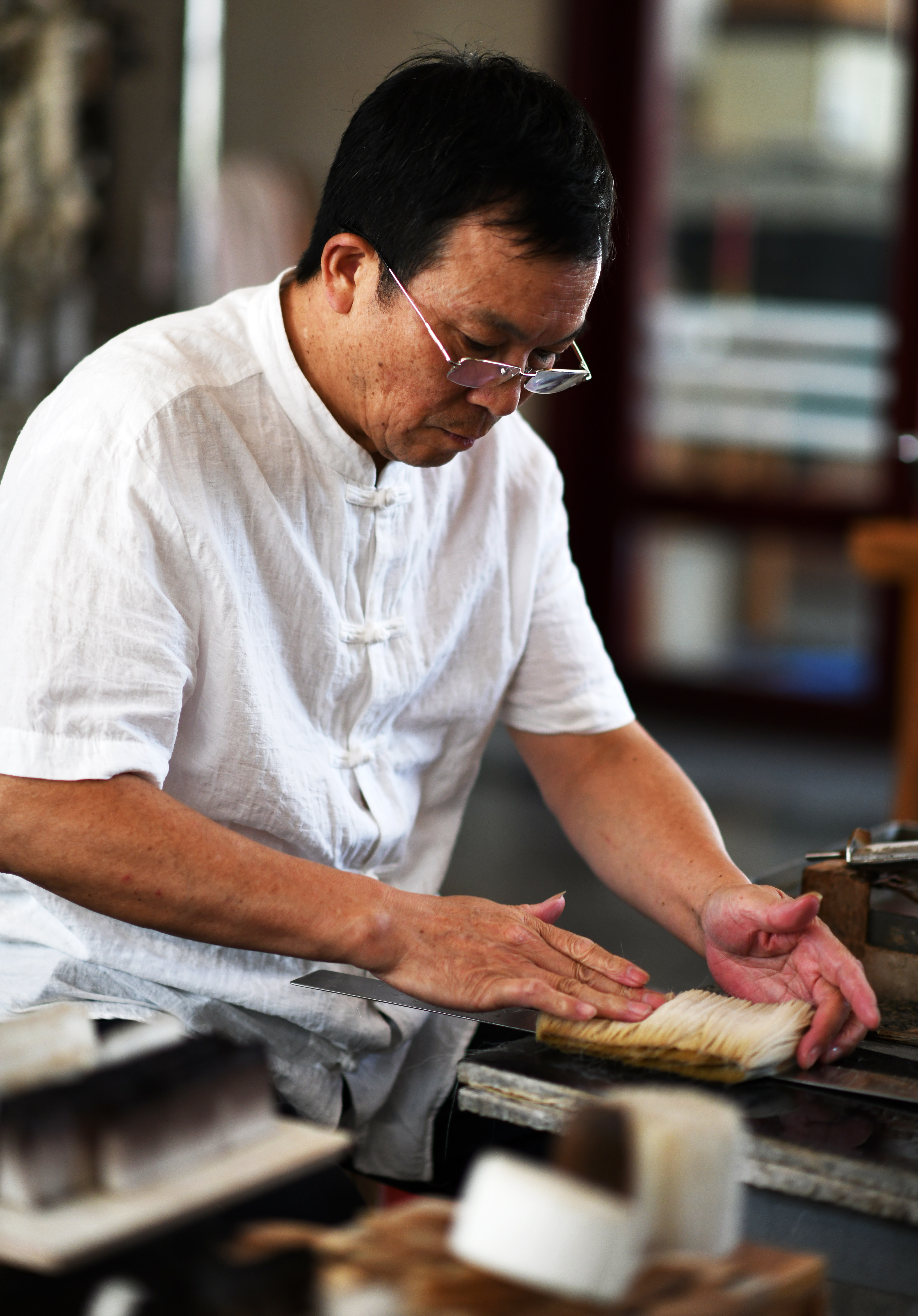 8月8日,周鹏程在自己的笔庄内制作毛笔.