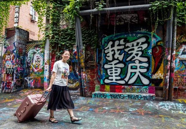 黄桷坪涂鸦街"我爱重庆"的涂鸦,以及一位拖着行李箱的外地游客.