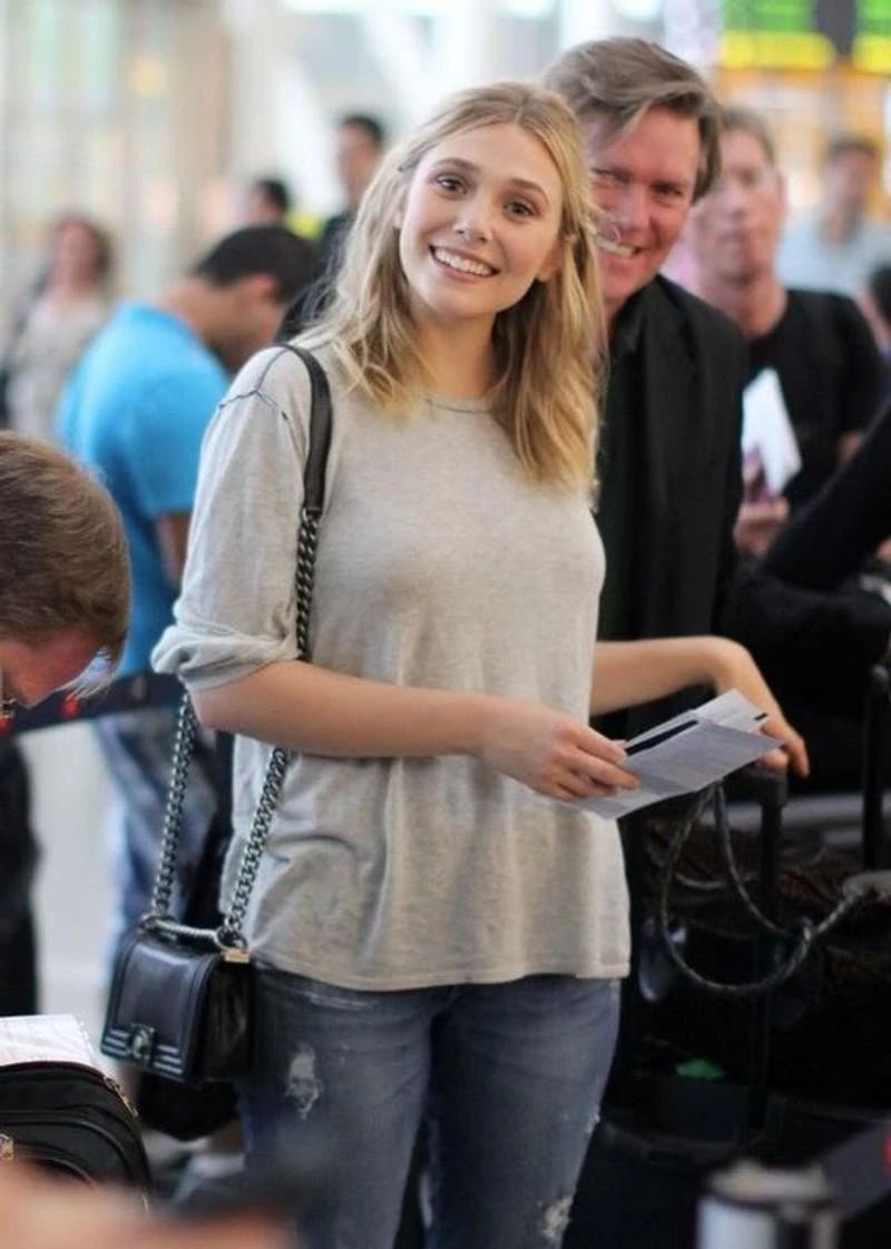 在某次活动上,伊丽莎白奥尔森身穿一袭华丽深蓝色平口长裙,双手叉腰