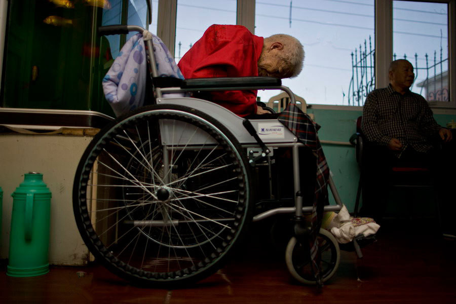 图中,一位老人坐在轮椅上睡着.