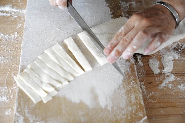 1 用擀面杖先把面团按压得扁平些. 7.2 用擀面杖把面片卷起来,来回擀.