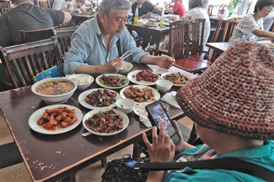 客人们在"燕龙"边吃着餐厅的最后一餐,边拍照留念.