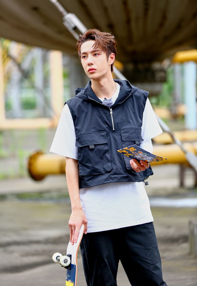 只见王俊凯身穿一件黑色夹克搭配灰色牛仔裤蹲在滑板上,暗色系的穿搭