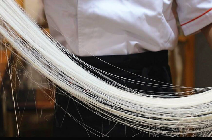 然后再撒上一层面粉,撒干面粉能防止面条粘连,经过苗师傅反复重合拉面