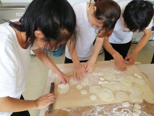 圖為隊員們忙著準備包餃子需要的餡料並一起擀皮.