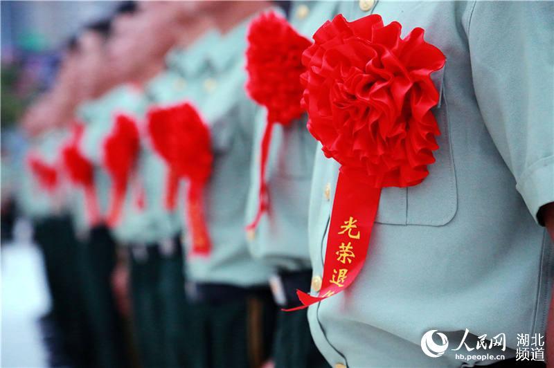60多名服役期满的老兵们胸前佩戴大红花,摘下帽徽领花,卸下警衔肩章