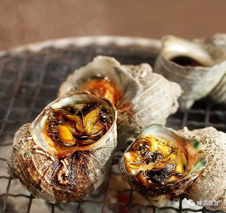 洗净的拳螺,取出螺肉切片再放回壳内后直接放到烧烤架上炙烤.