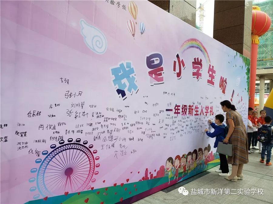 新生们在家长的陪伴下来到签名墙前.