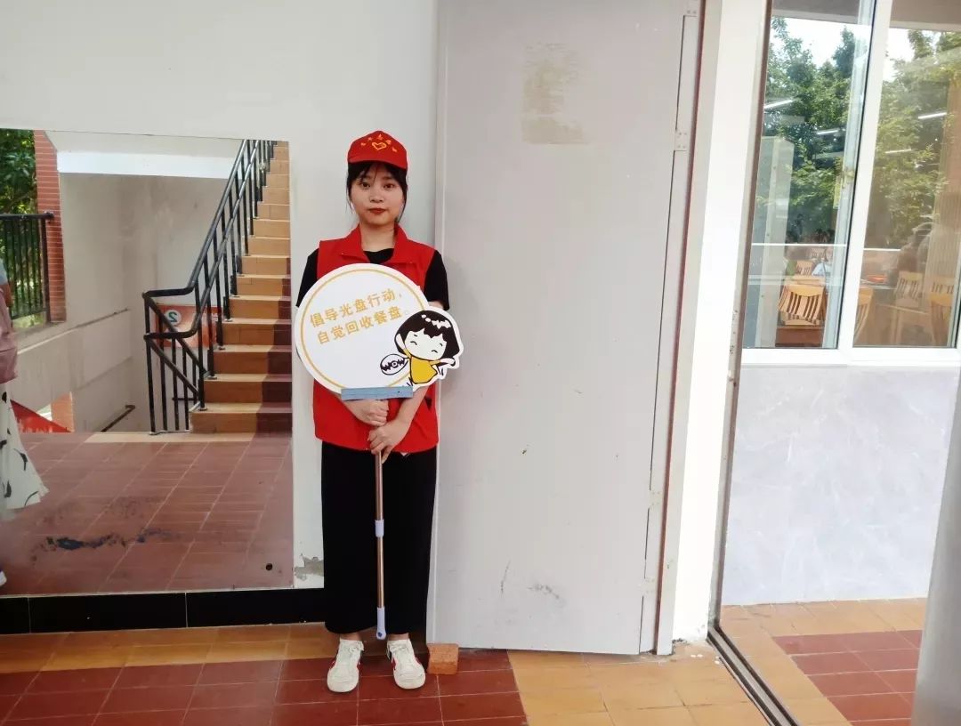 带着亲切的笑脸,在食堂门口,楼梯口手持文明食堂宣传标语牌,为新生