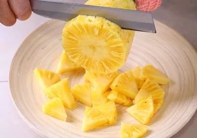 取出盘子,把6等份菠萝果肉,从头部往尾部依序横切,厚薄看个人喜好,即