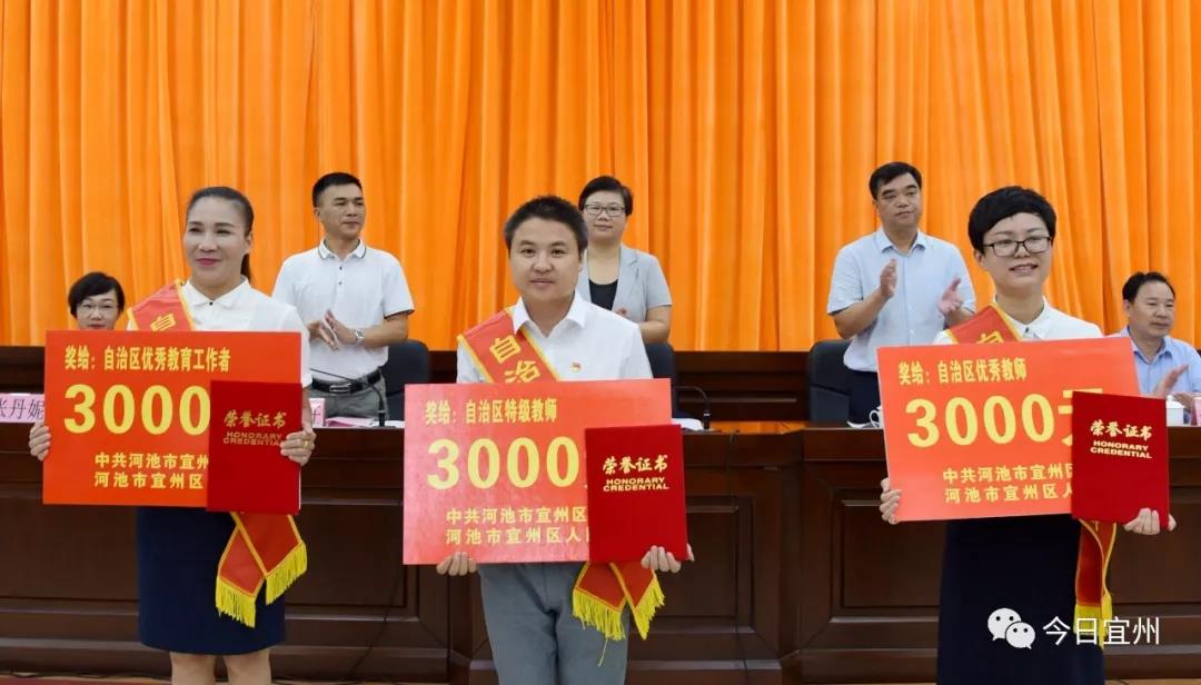 摄)区委副书记班华任宣读表彰文件;区政府副区长黄玲丹宣读《宜州区