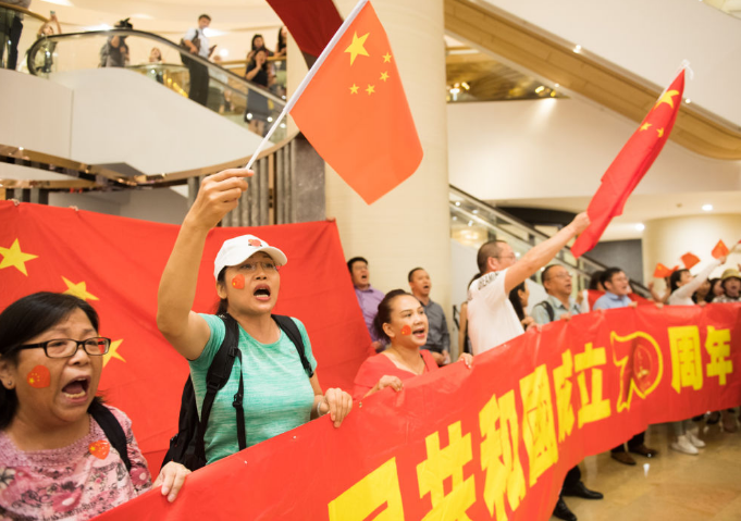 中华人民共和国成立70周年";几位市民还一起撑起五星红旗和紫荆花旗