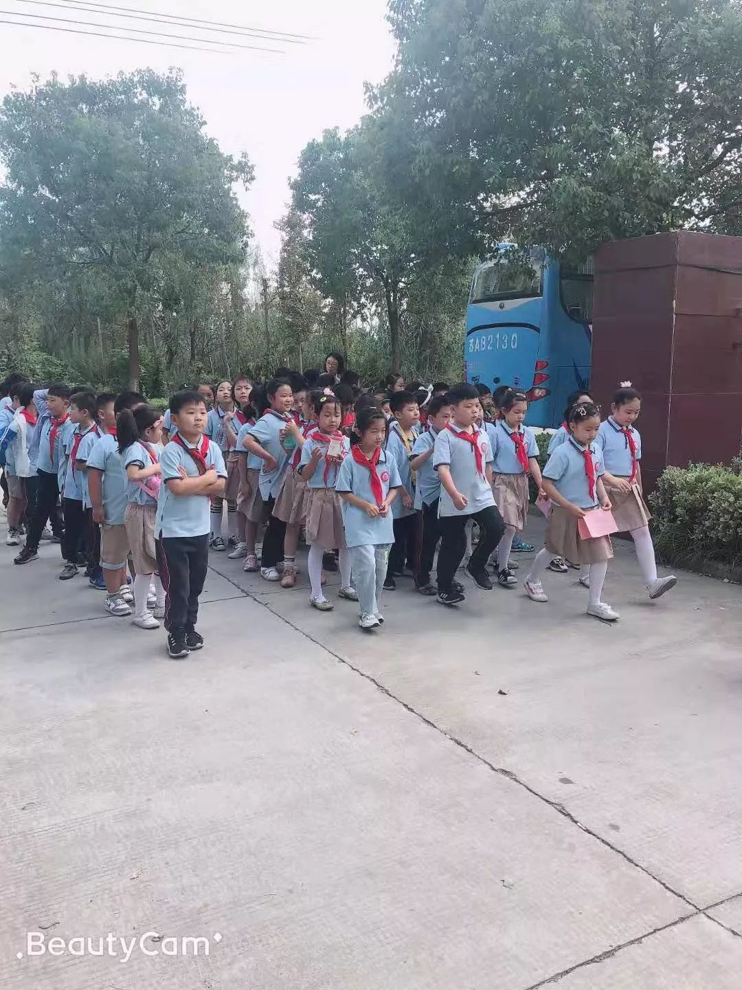 在学校门口整队待发大家着装整齐有序的排队乘坐大巴车前往敬老院