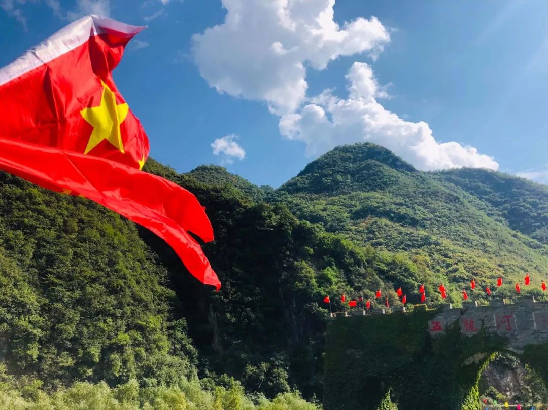 九天飞瀑上鲜艳的五星红旗与蓝天白云,青山绿水相呼应高空玻璃鹊桥上