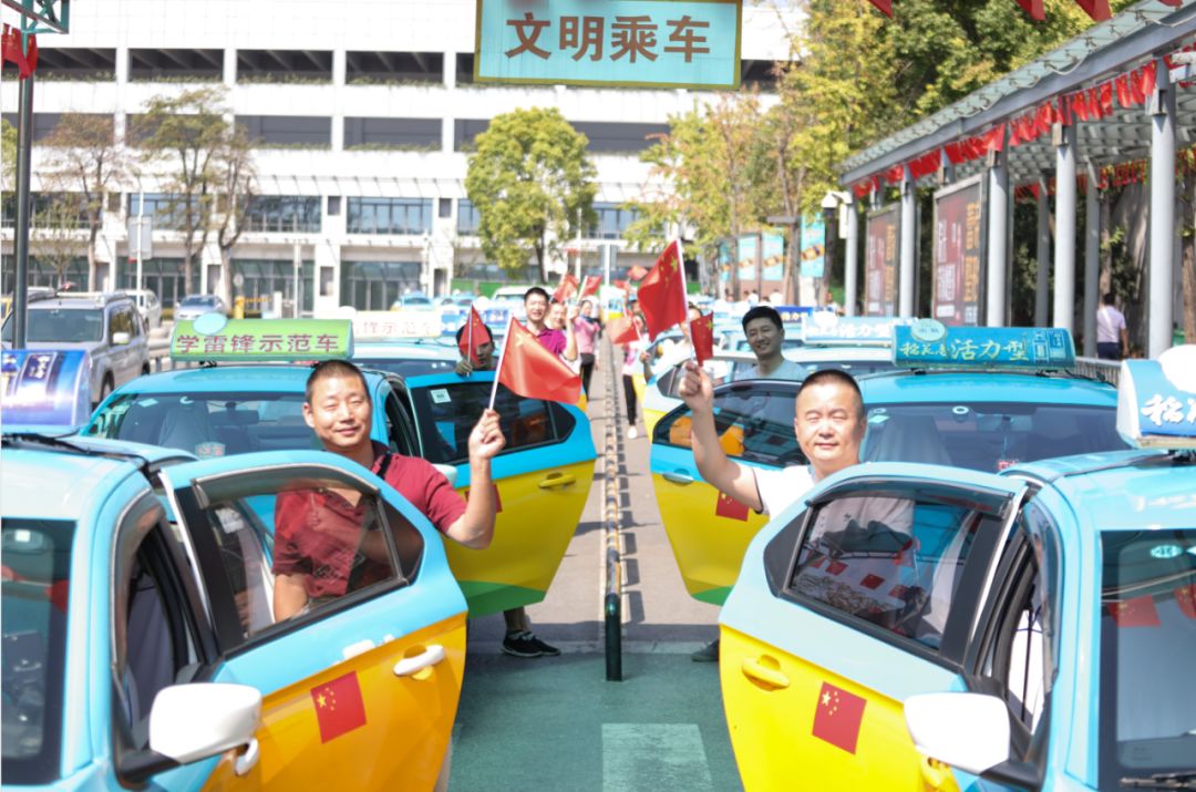 宜昌的哥的姐们在宜昌东站出租车乘车通道挥举国旗,庆祝新中国成立70