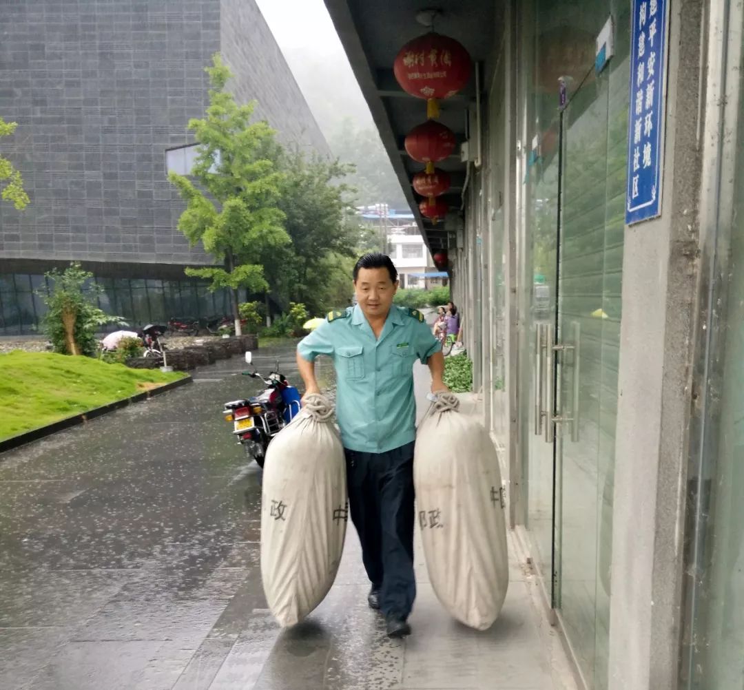 何先伦冒雨转运邮件何先伦在场镇投递报纸因为日常投递邮件需要走街串