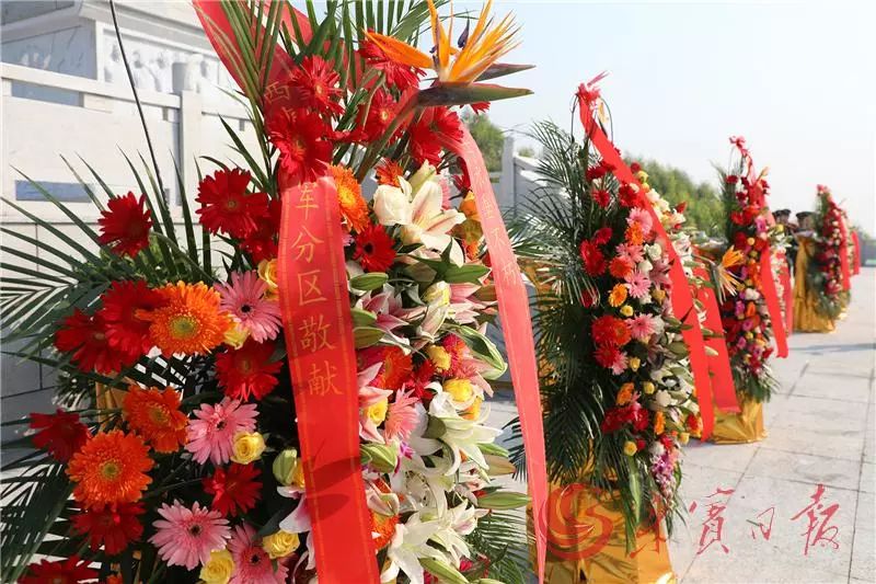 细心整理花篮上书写着"革命烈士永垂不朽"的缎带,寄托后人对革命先烈