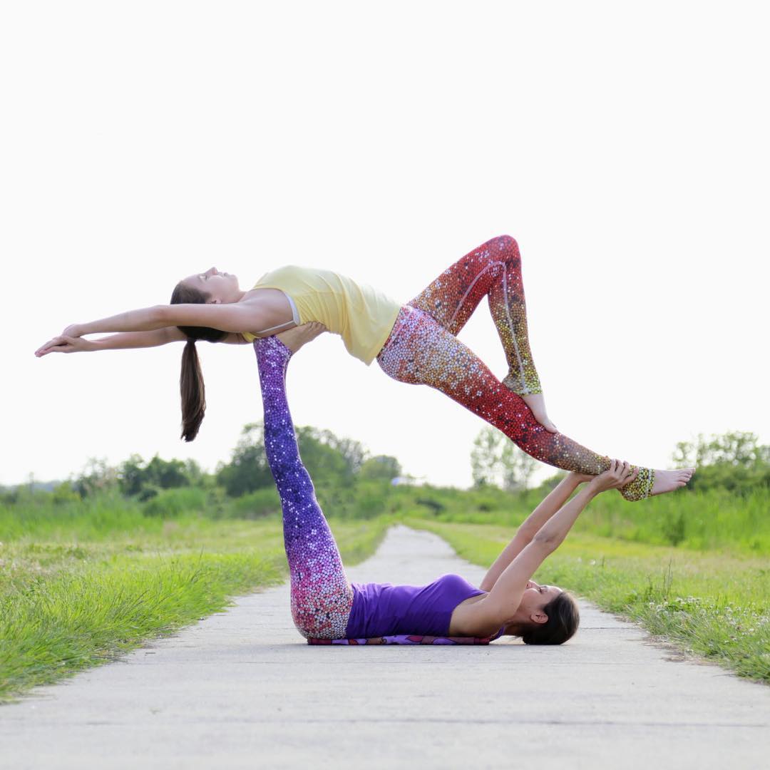 同伴躺在地面上,双手,双脚向上支撑,另一个人面向天空,双腿放在同伴的