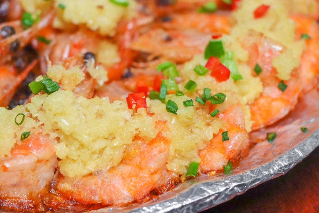 肥美的大虾身上铺满了蒜蓉,辣椒和葱花,放在锡纸盘上高温烤熟,外壳