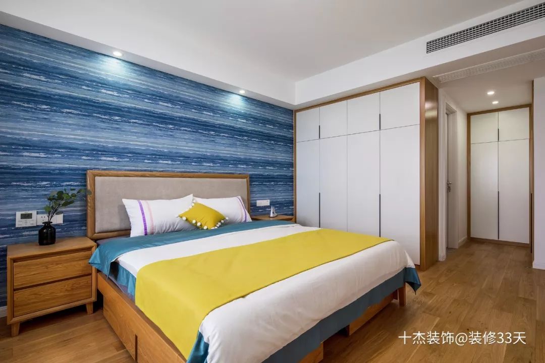 白色乳胶漆搭配床头海洋蓝纹理的墙纸,床侧置顶衣柜与入门右侧的