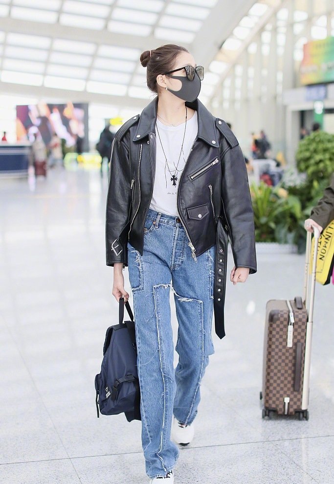 关晓彤上身穿着白色t恤,外面套着黑色机车皮衣,搭配补丁牛仔长裤,脚踩