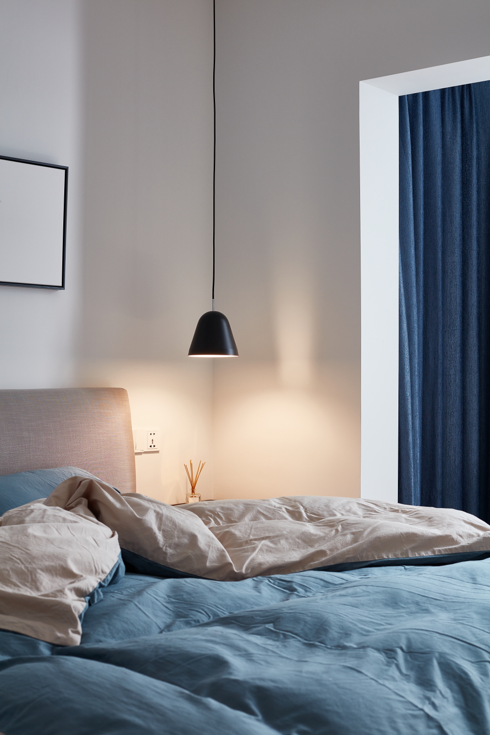 床头一盏黑色线形小吊灯也是很好看的呢~主卧阳台的窗帘也是蓝色的,很