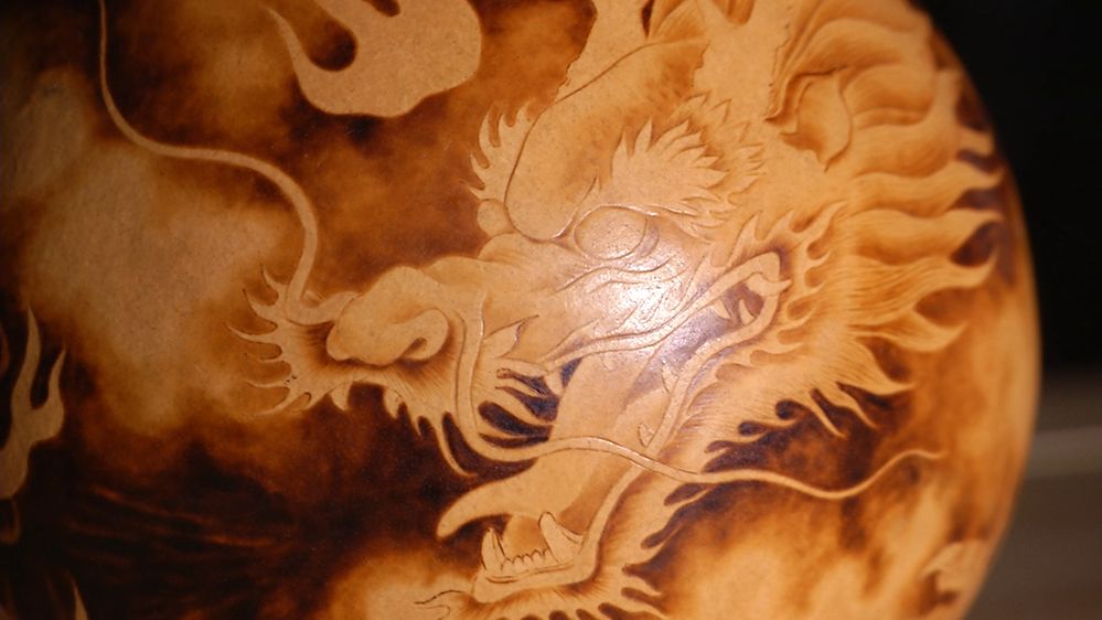 葫芦整体由一条龙环绕,龙头烙画于下部,颜色较深,龙口处喷出烈日般的