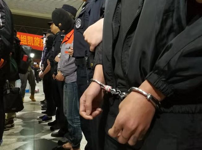 在民警押解下依次走出车厢4名戴着头套和手铐的男子停靠在合肥南站