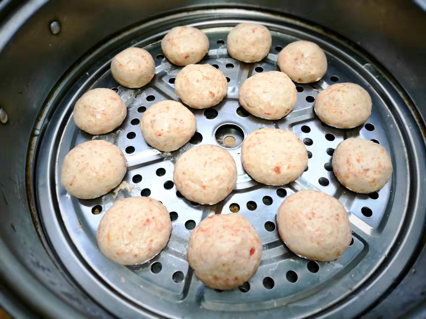 7,然后将面团揪成小团揉成小圆球状,小大适中就行,捏好的丸子摆在蒸笼