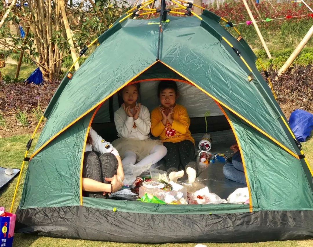 两位坐在帐篷里享用野餐的小朋友