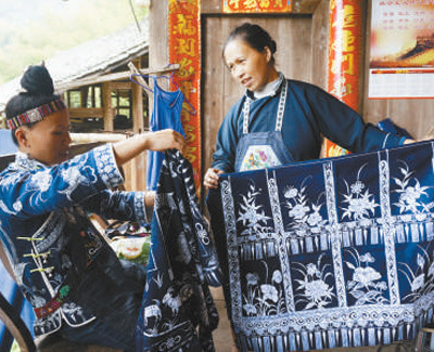 图为苗族妇女手持蓝花布料.