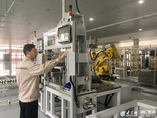 厂内工作人员正在新能源汽车汽车配件生产线上操作机器人手臂.