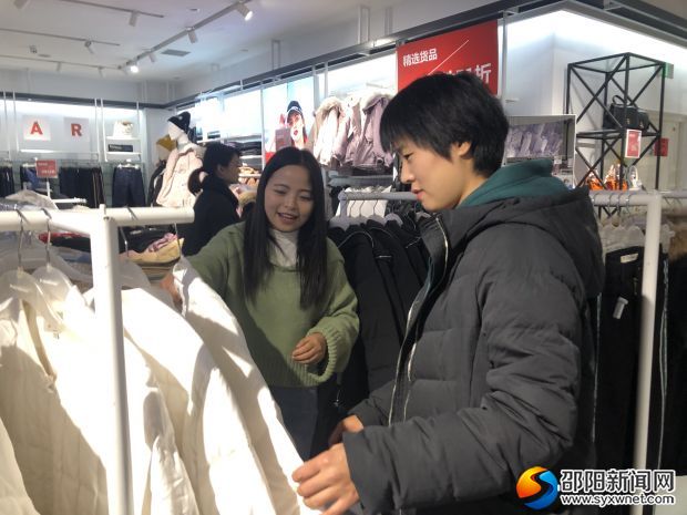 友阿商场内,销售正在为顾客推荐棉服.