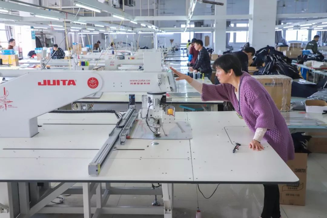 机头可以360度旋转的自动模板机另一边工人们正有条不紊地将服装裁片