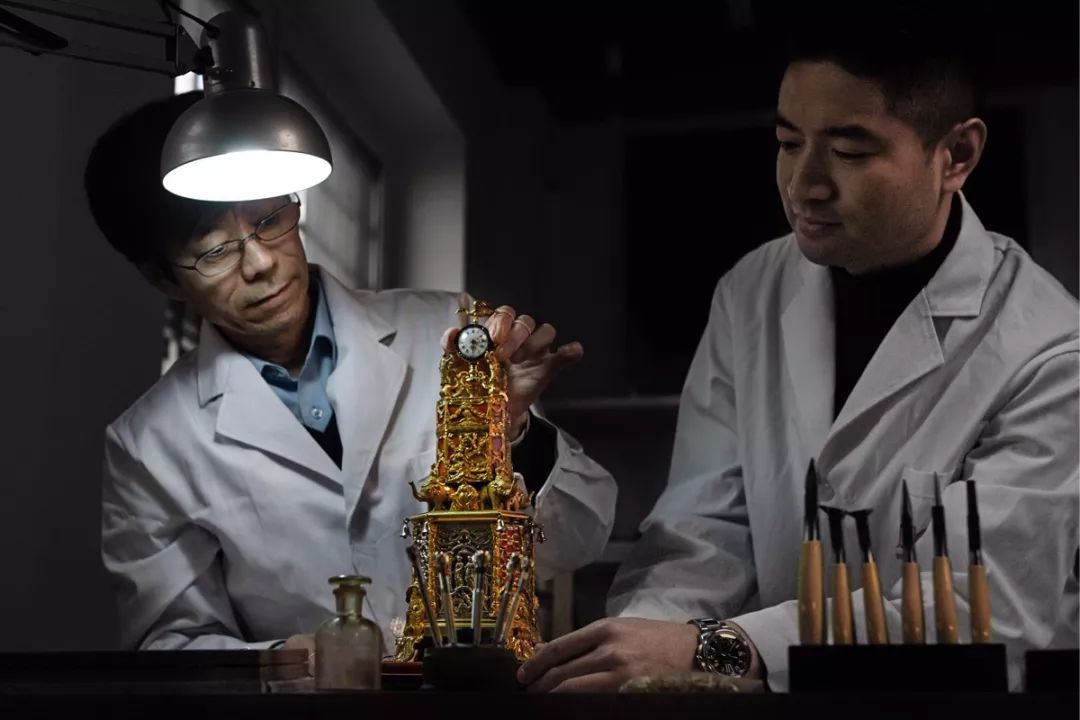 故宫博物院钟表保护修复专家王津与亓昊楠安装修复好的钟表文物