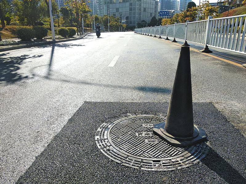 井盖更换后沥青仍在黏合牢固,市民看到锥筒请绕道而行 记者黎兆齐摄