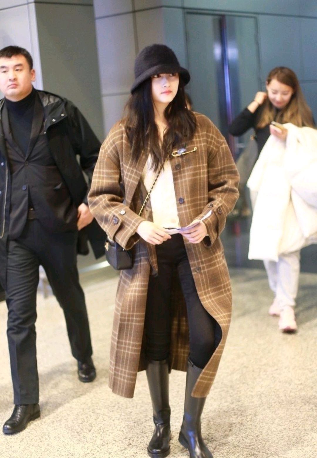 近期关晓彤身穿格纹大衣搭配黑色渔夫帽和中筒靴出现在机场,保暖时髦