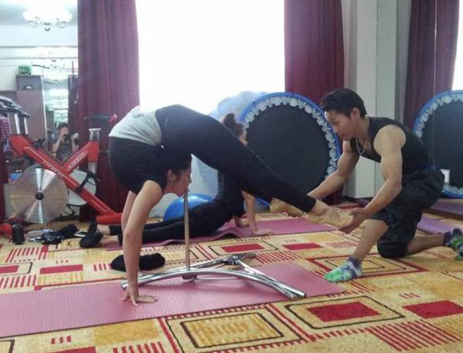 师父正在帮助女孩练习柔韧度,身体几乎成了折叠状态,队友训练完之后